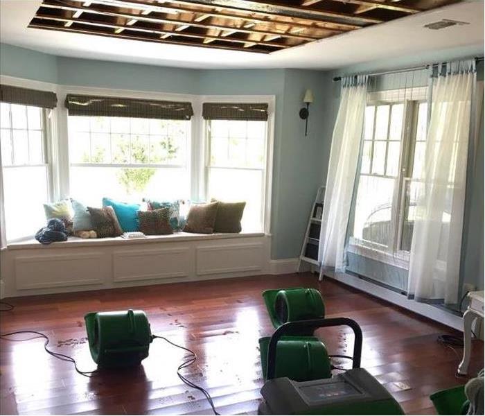 equipment on hardwood floor drying sunroom, portion of ceiling is removed showing timber