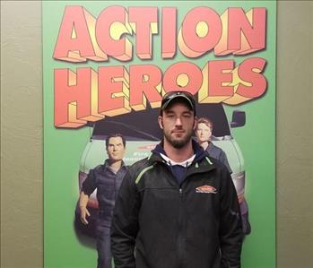male employee standing in front of a SERVPRO sign that says Action Heroes