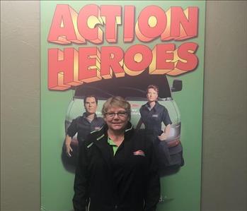 female employee standing in front of a SERVPRO sign that says Action Heroes