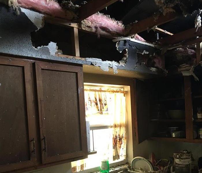 burned, exposed ceiling and messy countertop and window and cabinets from the fire