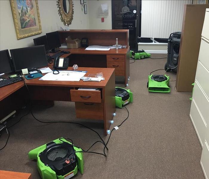 equipment drying out an office carpet with two desks, gray filing cabinets
