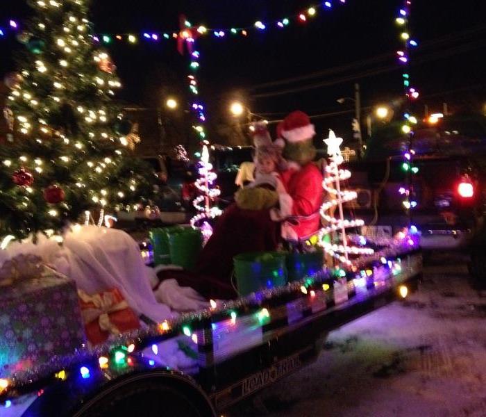 Parade float with Christmas lights and Santa with child sitting on it