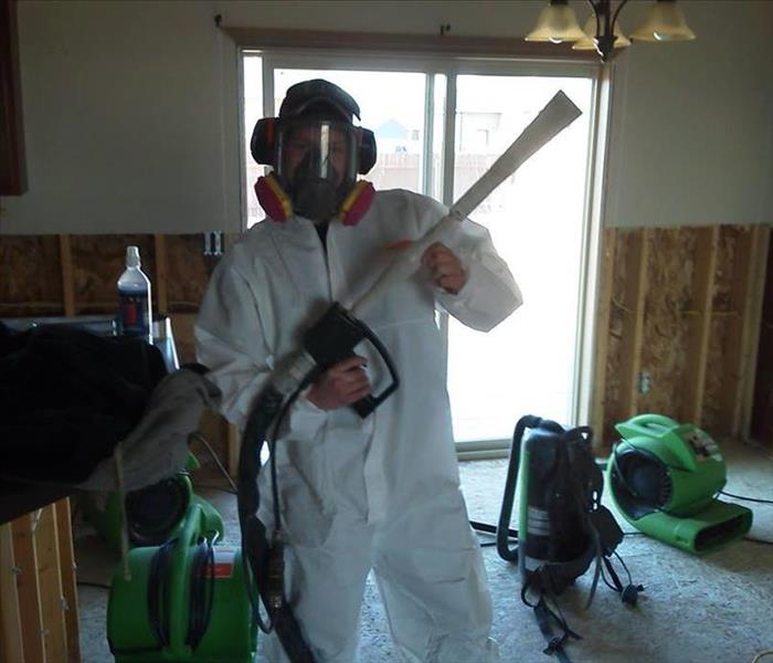 male in personal protective clothing holding a hose with a trigger nozzle
