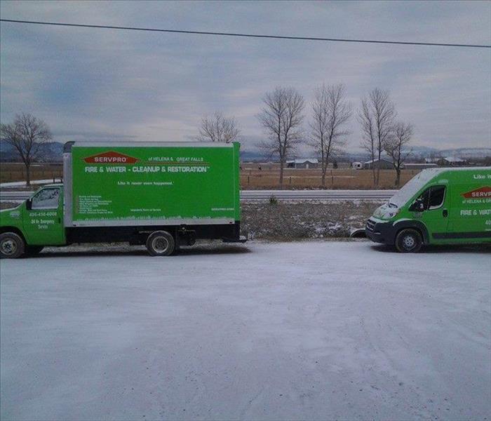 Snow covered parking lot with green SERVPRO box truck and van