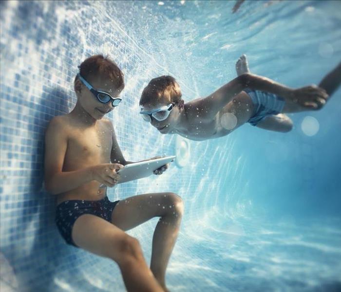 two boys underwater in a pool with a tablet