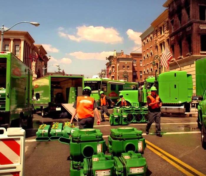 Green SERVPRO vans trucks and equipment in a street