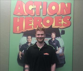 male employee standing in front of a SERVPRO sign that says Action Heroes