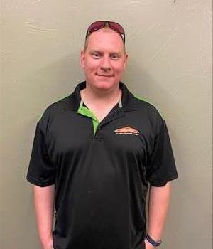 male employee in a black SERVPRO shirt in front of a tan wall
